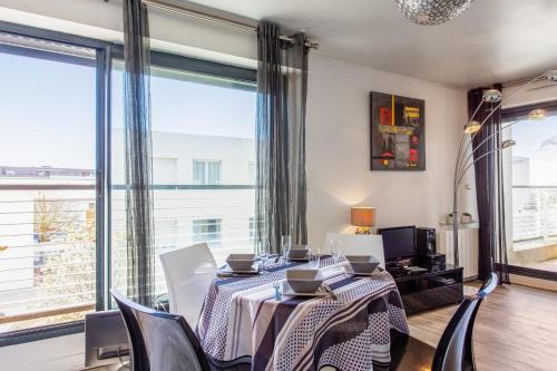 een eetkamer met een tafel en stoelen en een groot raam bij Nice flat with terrace & parking close to beaches in La Rochelle - Welkeys in La Rochelle