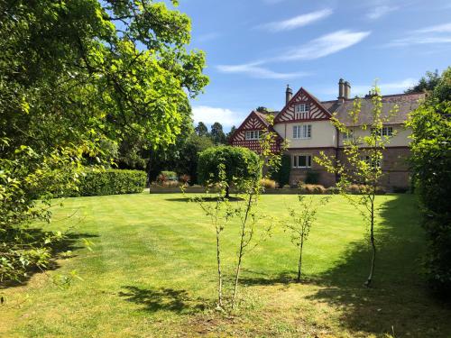a garden with two trees in front of a house at Rossal House Apartments in Inverness