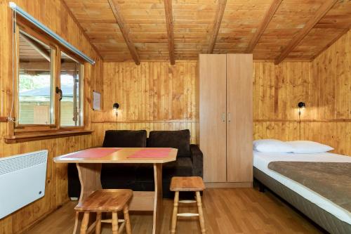 a small room with a bed and a table at Domki Letniskowe Kaprys in Pobierowo