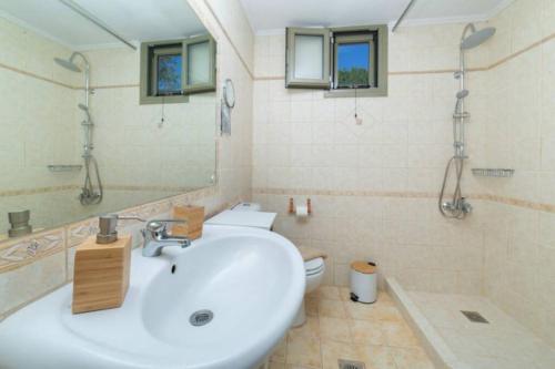 a bathroom with a sink and a toilet and a mirror at STATHI'S COTTAGE in Divarata