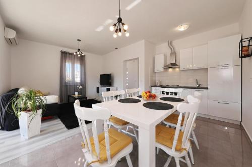 a kitchen and dining room with a white table and chairs at Apartman Lili in Zadar