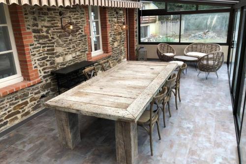 - une grande table en bois sur une terrasse avec des chaises dans l'établissement La Vallée Entre dunes et mer, un véritable havre de paix, à Barneville-Carteret