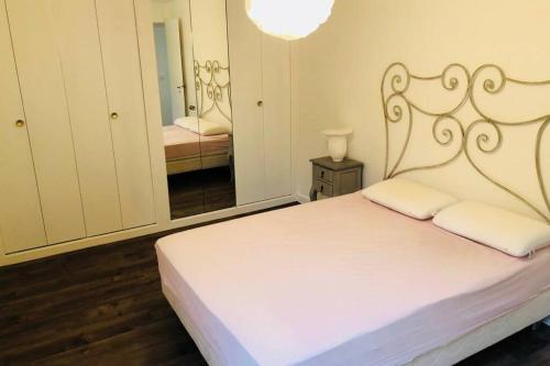 une chambre avec un lit blanc et un miroir dans l'établissement La Vallée Entre dunes et mer, un véritable havre de paix, à Barneville-Carteret