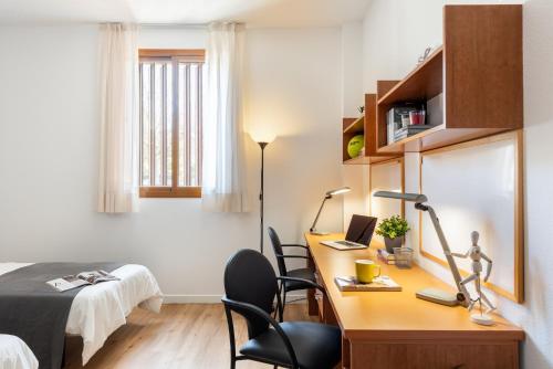 a bedroom with a desk with a laptop and a bed at Micampus Bormujos Student Residence in Bormujos