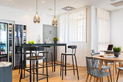 a kitchen with a bar with stools and tables at Micampus Bormujos Student Residence in Bormujos