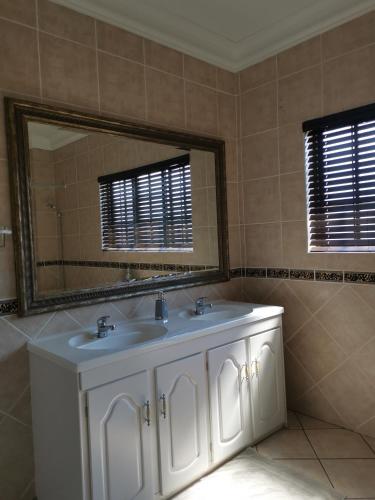 a bathroom with a white sink and a mirror at Klyne Jiweel Guesthouse in Pretoria