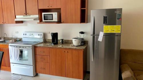 Una cocina con refrigerador de acero inoxidable y microondas. en Condominios Costa Linda, en Jacó