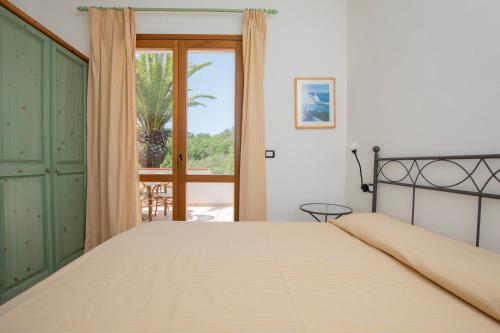 Un dormitorio con una cama grande y una ventana. en Villa le Palme, en Capoliveri