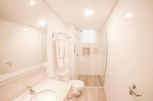 a white bathroom with a toilet and a shower at Hotel Vila Germânica in Piratuba