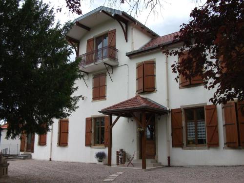 ein großes weißes Haus mit Holzfenstern und einer Tür in der Unterkunft Villa Sainte Barbe in Mirecourt
