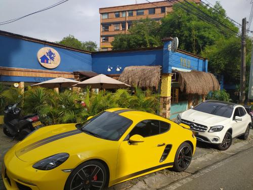 un coche amarillo estacionado junto a un coche blanco en Yolo Hostel Medellin en Medellín