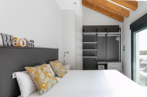 a bedroom with a white bed and a black closet at Arenal Suites Alicante in Alicante