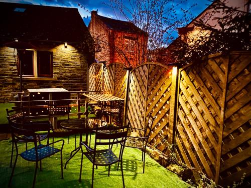a patio with chairs and a table and a fence at Higgin Bridge House in Holmfirth