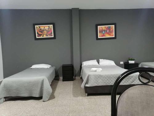 a bedroom with two beds and two pictures on the wall at Suite Trujillo in Trujillo
