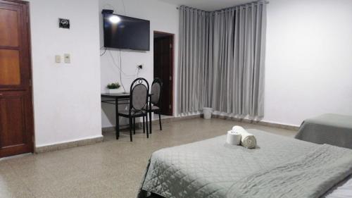 a bedroom with a bed and a desk and a television at Suite Trujillo in Trujillo