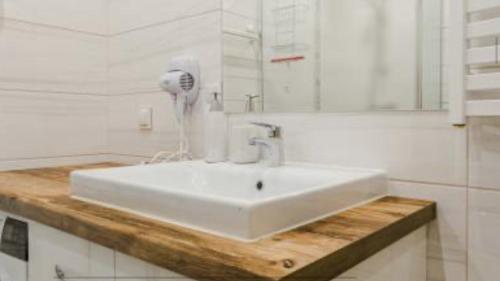 ein Badezimmer mit einem weißen Waschbecken und einem Haartrockner in der Unterkunft Apartament San in Łeba