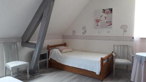 1 dormitorio pequeño con 1 cama y 2 sillas en Gîte La Fortaiserie, en Rillé
