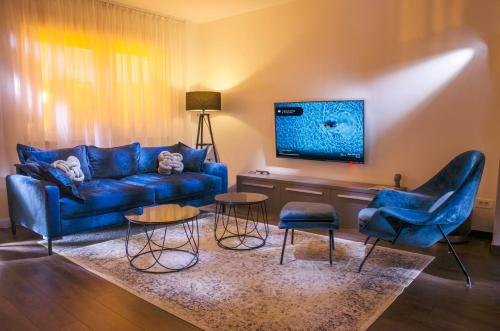 uma sala de estar com um sofá azul e cadeiras em Villa Kap em Zagreb