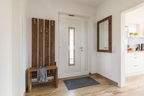 a white hallway with a mirror and a chair at Naturpark-5 Sterne Ferienhaus-Kamin-Sauna-See in Krakow am See