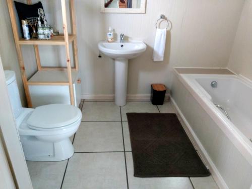 a bathroom with a toilet and a sink and a tub at LaPlek Guest Suite in East London