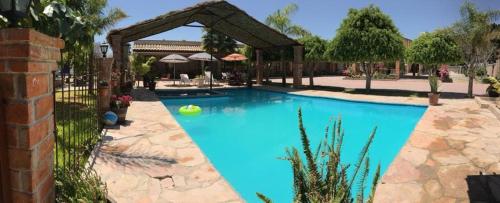 una gran piscina azul con una valla en Hotel Posada Rancho Los Laureles 