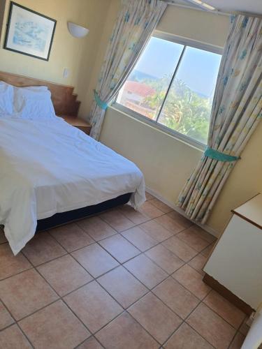 a bedroom with a bed and a large window at Kapenta Bay Holiday Resort Port Shepstone unit 12 in Port Shepstone