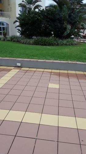 a tiled courtyard with grass and palm trees in a building at Kapenta Bay Holiday Resort Port Shepstone unit 12 in Port Shepstone