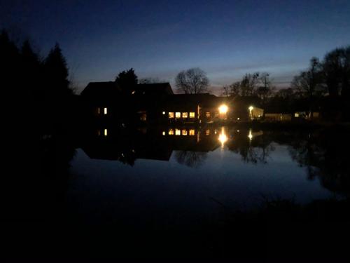 a house at night with the lights on the water at Malswick Mill in Newent