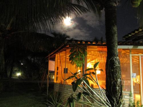 a house with a palm tree in front of it at night at Hotel Enseada Maracajaú in Maracajaú