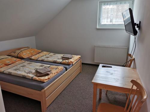 a bedroom with two beds and a table and a desk at Apartmány u Hastrmana in Vyšší Brod