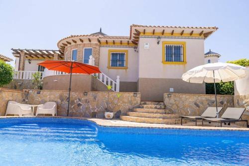 een zwembad met twee stoelen en een parasol en een huis bij Casa Lilly-Rose, a beautiful 3 bedroom detached villa a short walk to the Villamartin Plaza & Golf course in Villamartin
