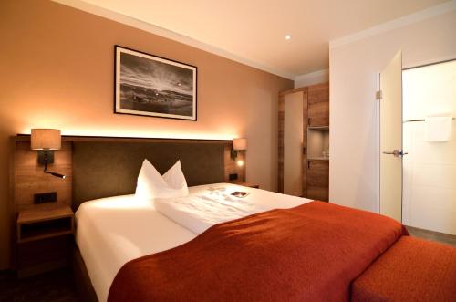 a hotel room with a bed with an orange blanket at Lindenberger Hof in Lindenberg im Allgäu