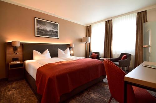 a hotel room with a bed with a red blanket at Lindenberger Hof in Lindenberg im Allgäu