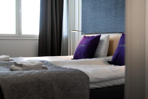 a hotel room with two beds with purple pillows at Hotelli Loimu by UHANDA in Raisio