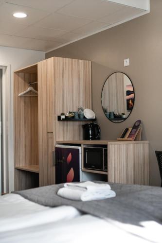a bedroom with a bed with a mirror and a microwave at Hotelli Loimu by UHANDA in Raisio