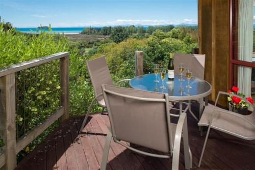 a table and chairs on a balcony with a view of the ocean at Ocean View Chalets in Marahau