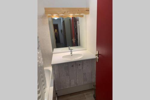 W łazience znajduje się umywalka i lustro. w obiekcie Logement 4/6 personnes à la montagne avec piscine w mieście Saint-Sorlin-dʼArves
