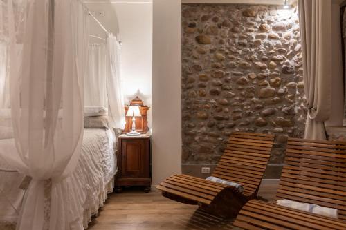 a bedroom with two wooden chairs and a stone wall at GardaBeds Adults Only in Castelnuovo del Garda