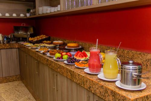a buffet line with plates of food and drinks at Domus Hotel Trindade Canaã dos Carajás in Canaã dos Carajás