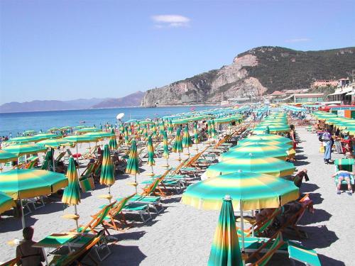 a beach filled with lots of green and yellow umbrellas at Casa Vacanze Isophylla in Finale Ligure