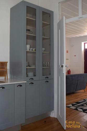 a kitchen with white cabinets and a blue couch at Casa dos Aleluia in Coimbra