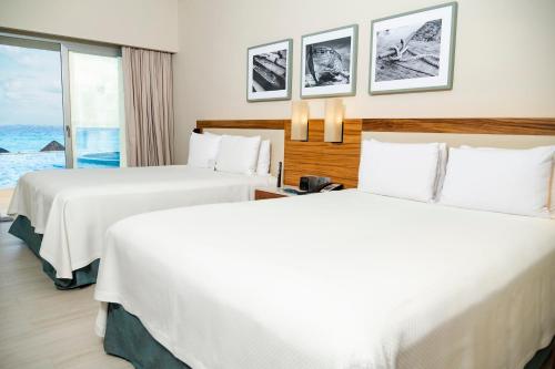 two beds in a hotel room with a view of the ocean at Emporio Cancun - Buy All Inclusive Option in Cancún