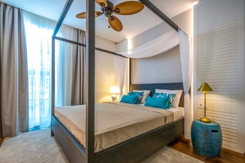 a bedroom with a canopy bed with blue pillows at BalaLake Resort in Szántód