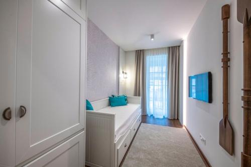 a white bedroom with blue pillows on a white couch at BalaLake Resort in Szántód