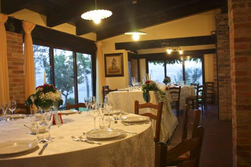 una sala da pranzo con tavoli lunghi e tovaglie bianche di Agriturismo La Corte Sul Lago a Cingoli