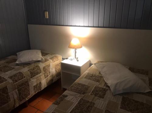 a bedroom with two beds and a lamp on a night stand at Apartamentos Sulla Collina Centro de Gramado localizado próximo da rua Coberta in Gramado