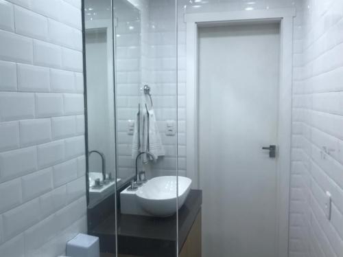 a bathroom with a sink and a glass shower door at Apartamentos Sulla Collina Centro de Gramado localizado próximo da rua Coberta in Gramado