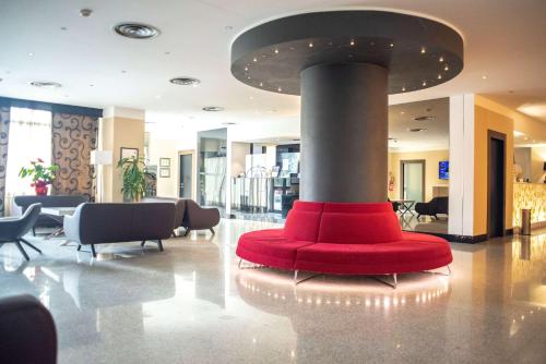 a lobby with a red couch in the middle at Best Western Hotel Quattrotorri in Perugia