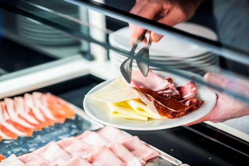 a person holding a plate of food with a fork and knife at Best Western Hotel Quattrotorri in Perugia