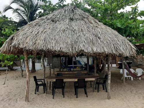 a table and chairs under a straw umbrella on the beach at Casa Madrigueña in Rincón